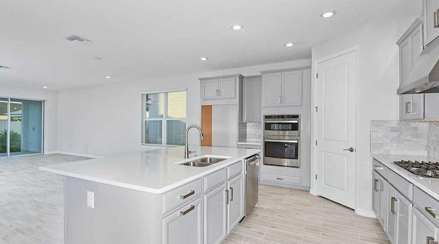 33306 Castaway Loop, Wesley Chapel, FL 33543 - kitchen featuring a sink, appliances with stainless steel finishes, gray cabinetry, tasteful backsplash, and light wood-type flooring