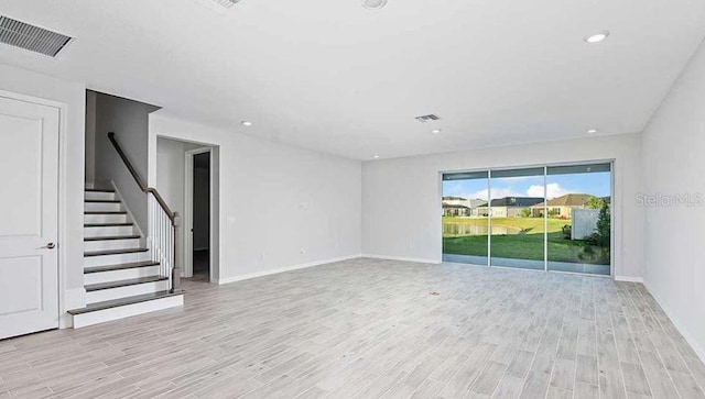 33306 Castaway Loop, Wesley Chapel, FL 33543 - unfurnished living room featuring light wood finished floors, stairway, baseboards, and recessed lighting