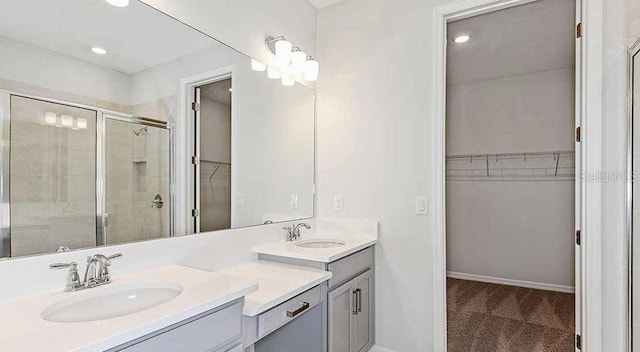 33306 Castaway Loop, Wesley Chapel, FL 33543 - bathroom featuring double vanity, a walk in closet, a shower stall, baseboards, and recessed lighting