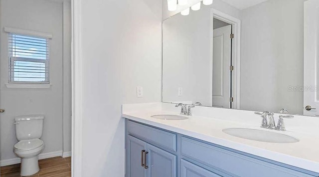 33306 Castaway Loop, Wesley Chapel, FL 33543 - full bathroom with double vanity, toilet, wood finished floors, and baseboards