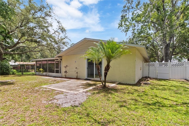 39721 Meadowood Loop, Zephyrhills, FL 33542 - back of property featuring a sunroom, a patio, stucco siding, and a gate