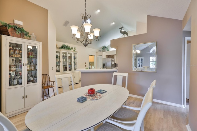 1111 Golfview Woods Dr Unit 1111, Sun City Center, FL 33573 - dining area featuring vaulted ceiling, a chandelier, light wood-type flooring, and baseboards