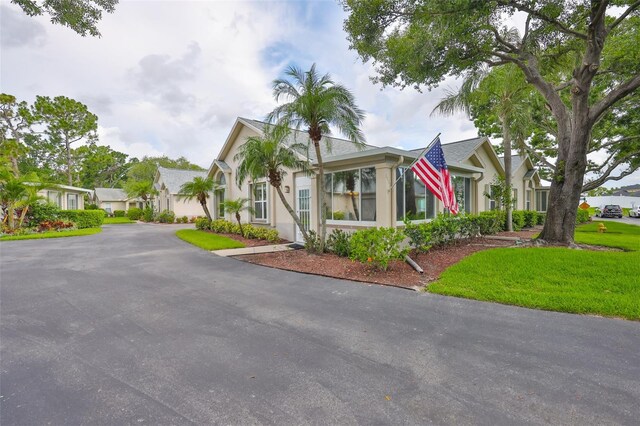 1111 Golfview Woods Dr Unit 1111, Sun City Center, FL 33573 - view of front facade with stucco siding, driveway, a front lawn, and a residential view