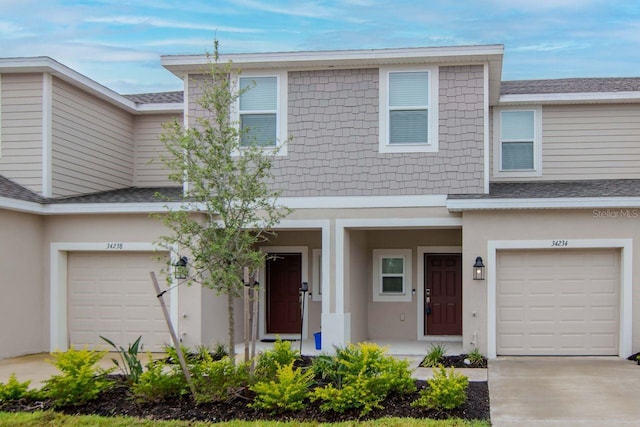 34234 Polacca Ln, Wesley Chapel, FL 33543 - townhome / multi-family property with a garage, a shingled roof, stucco siding, and a porch