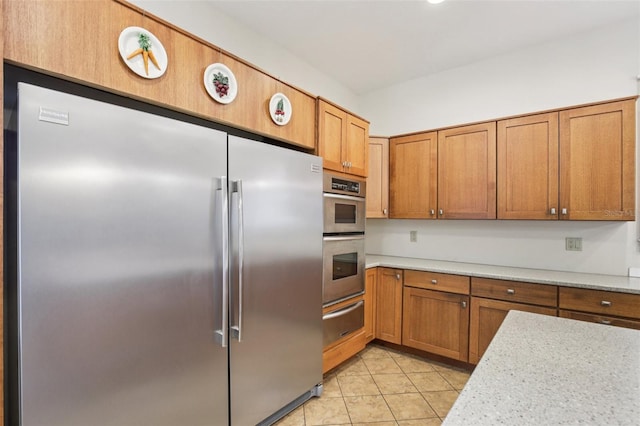 1803 143rd Ct E, Bradenton, FL 34212 - kitchen with stainless steel appliances, a warming drawer, light countertops, brown cabinetry, and light tile patterned flooring