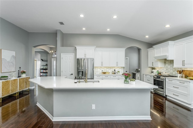 9608 Greenpointe Dr, Tampa, FL 33626 - kitchen featuring appliances with stainless steel finishes, arched walkways, a large island with sink, vaulted ceiling, and white cabinetry