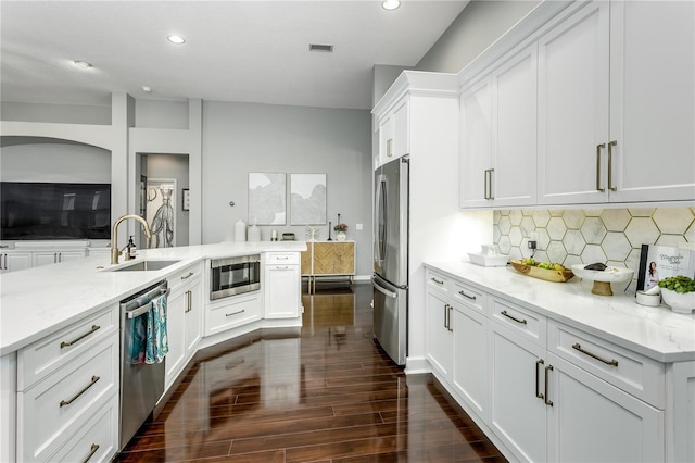 9608 Greenpointe Dr, Tampa, FL 33626 - kitchen featuring stainless steel appliances, a sink, dark wood-style floors, white cabinets, and backsplash