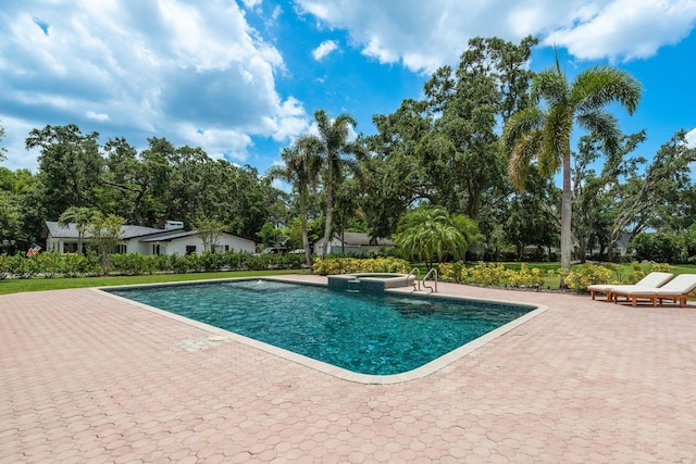 2395 Campbell Rd, Clearwater, FL 33765 - view of swimming pool featuring a pool with connected hot tub, a patio area, and view of wooded area
