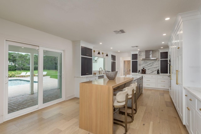 2395 Campbell Rd, Clearwater, FL 33765 - kitchen featuring wall chimney exhaust hood, open shelves, backsplash, a sink, and light wood-style flooring
