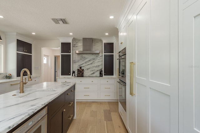 2395 Campbell Rd, Clearwater, FL 33765 - kitchen with wall chimney range hood, a sink, tasteful backsplash, light wood finished floors, and white cabinetry