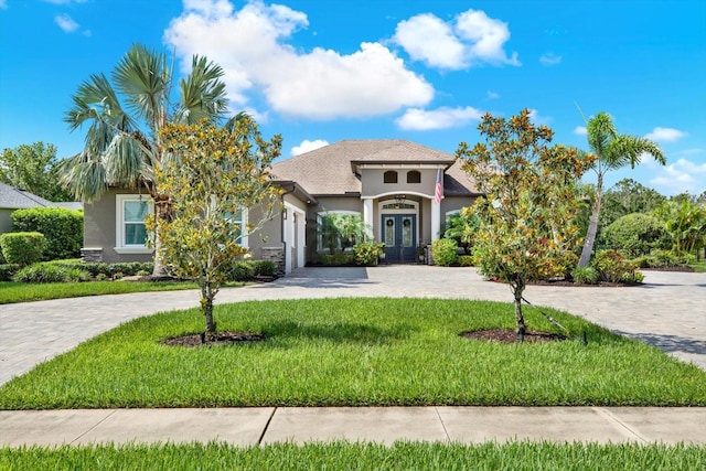 15415 Mulholland Rd, Parrish, FL 34219 - mediterranean / spanish house with french doors, stucco siding, curved driveway, a front lawn, and an attached garage