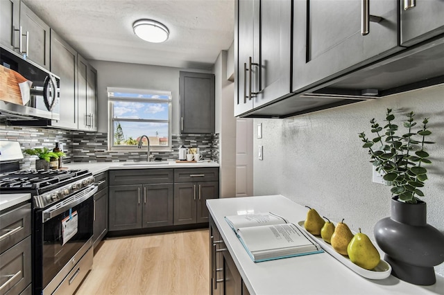 2960 59th St S Unit 303, Gulfport, FL 33707 - kitchen with stainless steel appliances, a sink, tasteful backsplash, light countertops, and light wood finished floors