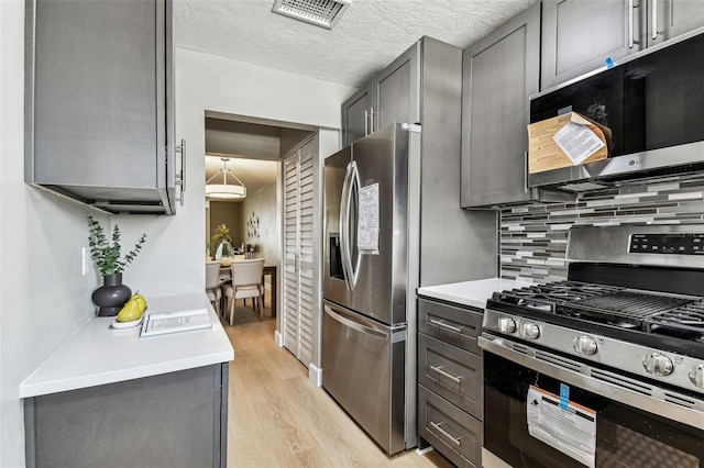2960 59th St S Unit 303, Gulfport, FL 33707 - kitchen featuring stainless steel appliances, light wood-style flooring, backsplash, and gray cabinetry