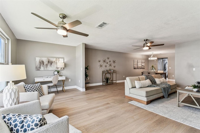 2960 59th St S Unit 303, Gulfport, FL 33707 - living room featuring ceiling fan, light wood-style floors, baseboards, and a textured ceiling
