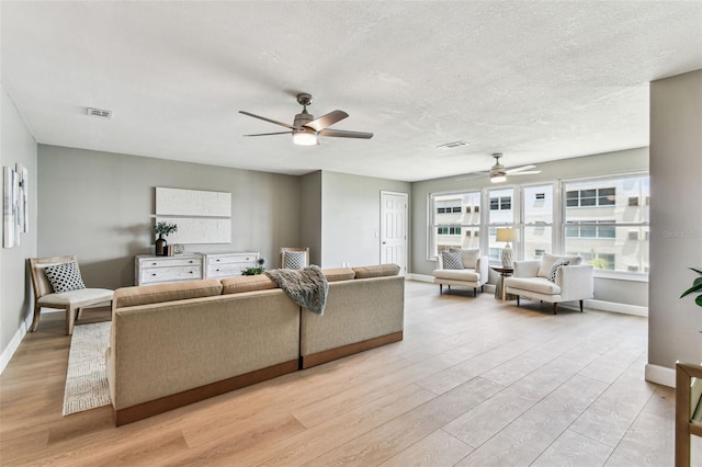 2960 59th St S Unit 303, Gulfport, FL 33707 - living room featuring ceiling fan, light wood finished floors, baseboards, and a textured ceiling