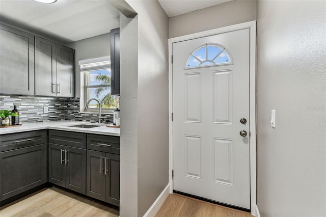 2960 59th St S Unit 303, Gulfport, FL 33707 - kitchen featuring light wood-style flooring, backsplash, light countertops, a sink, and baseboards