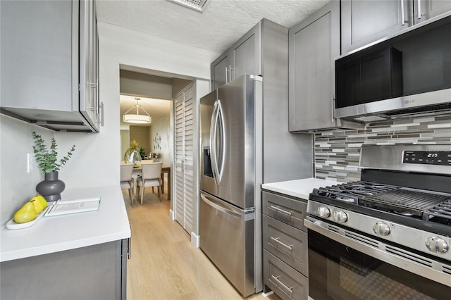 2960 59th St S Unit 303, Gulfport, FL 33707 - kitchen with appliances with stainless steel finishes, gray cabinets, light wood finished floors, decorative backsplash, and light countertops