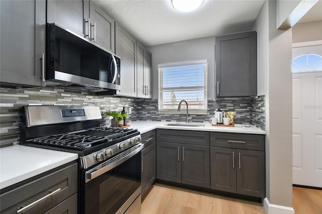2960 59th St S Unit 303, Gulfport, FL 33707 - kitchen with stainless steel range with gas cooktop, light wood-type flooring, light countertops, backsplash, and gray cabinets