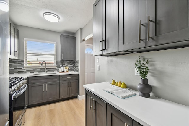 2960 59th St S Unit 303, Gulfport, FL 33707 - kitchen with stainless steel gas range, decorative backsplash, light countertops, and light wood finished floors