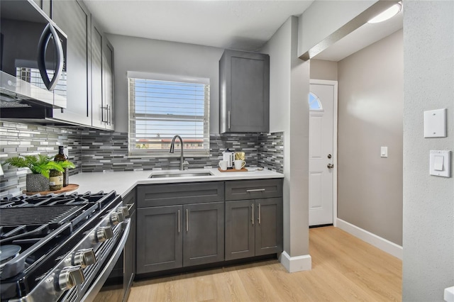 2960 59th St S Unit 303, Gulfport, FL 33707 - kitchen with appliances with stainless steel finishes, gray cabinets, backsplash, light wood finished floors, and light countertops