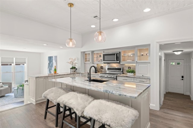 146 26th Ave NE, Saint Petersburg, FL 33704 - kitchen with appliances with stainless steel finishes, wood finished floors, a kitchen island with sink, a sink, and recessed lighting