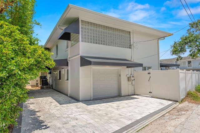 146 26th Ave NE, Saint Petersburg, FL 33704 - view of front facade with stucco siding, a garage, a gate, and central air condition unit