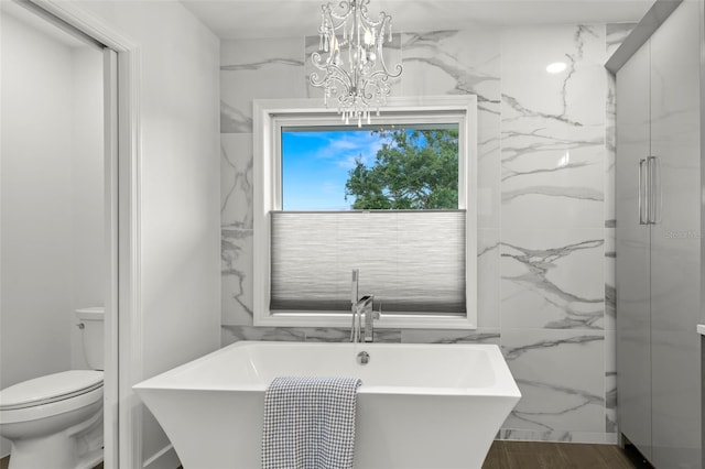 146 26th Ave NE, Saint Petersburg, FL 33704 - full bath featuring toilet, a freestanding tub, a chandelier, and tile walls