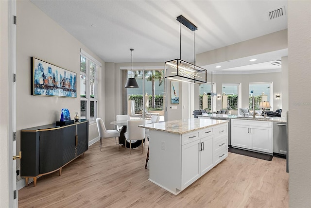 100 Beach Dr NE Unit 301, Saint Petersburg, FL 33701 - kitchen featuring white cabinetry, light wood-style floors, dishwasher, light stone countertops, and a center island
