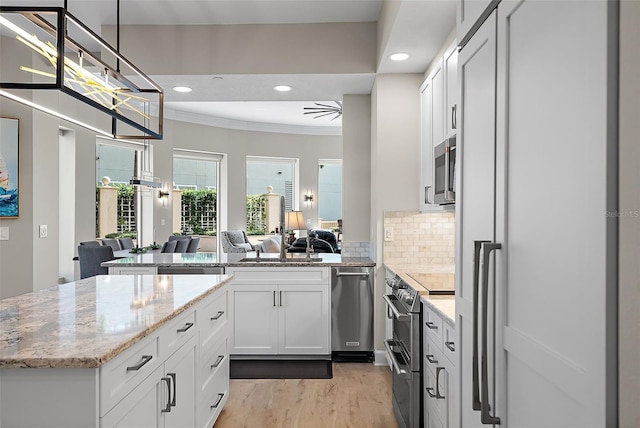100 Beach Dr NE Unit 301, Saint Petersburg, FL 33701 - kitchen with stainless steel appliances, open floor plan, light wood finished floors, crown molding, and light stone countertops