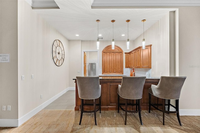 100 Beach Dr NE Unit 301, Saint Petersburg, FL 33701 - kitchen with stainless steel refrigerator, a breakfast bar area, hanging light fixtures, baseboards, and a peninsula