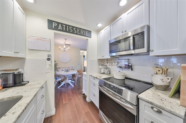 1224 W Del Webb Blvd, Sun City Center, FL 33573 - kitchen with stainless steel appliances, decorative backsplash, a chandelier, white cabinets, and wood finished floors