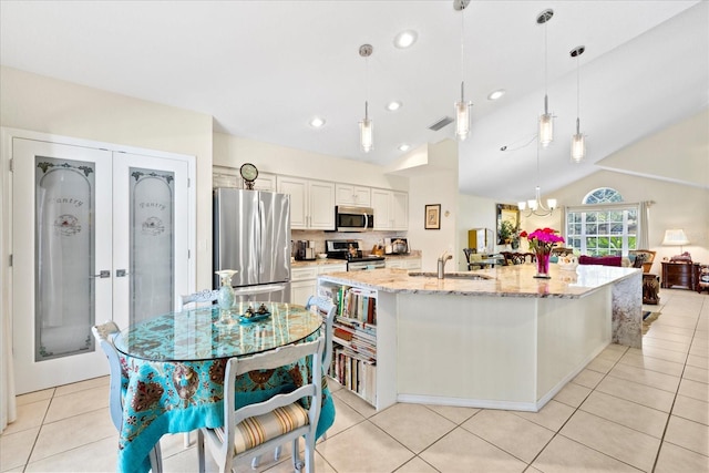 4047 Eagle Cove W Dr, Palm Harbor, FL 34685 - kitchen with stainless steel appliances, light tile patterned flooring, light stone counters, hanging light fixtures, and french doors