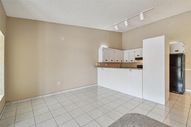 3389 Crystal Ct E J, Unit J, Palm Harbor, FL 34685 - kitchen with freestanding refrigerator, rail lighting, a kitchen bar, white cabinetry, and light tile patterned floors