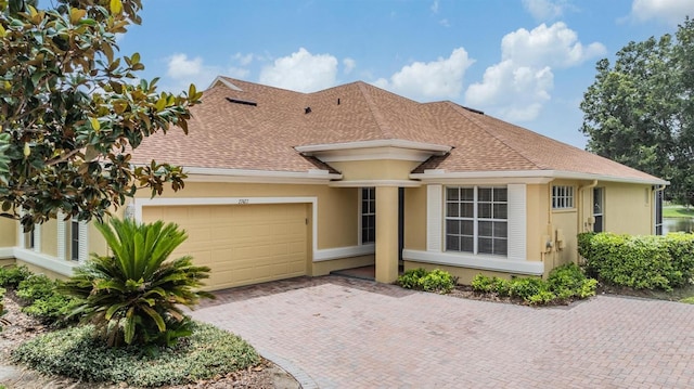 27427 Mistflower Dr, Wesley Chapel, FL 33544 - view of front of house featuring an attached garage, stucco siding, decorative driveway, and a shingled roof