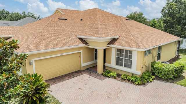 27427 Mistflower Dr, Wesley Chapel, FL 33544 - view of front of property with a garage, stucco siding, a shingled roof, and decorative driveway
