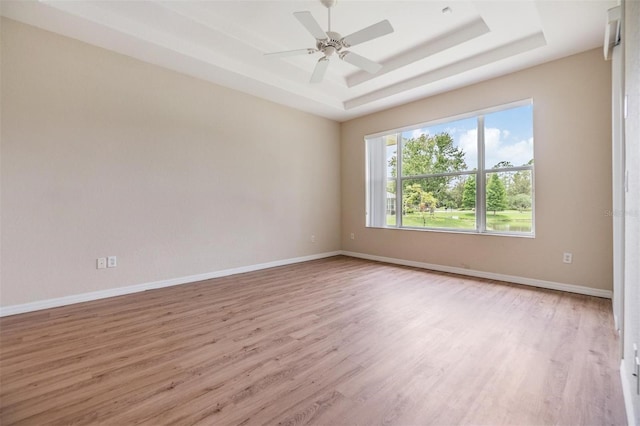 27427 Mistflower Dr, Wesley Chapel, FL 33544 - empty room featuring light wood-style floors, a tray ceiling, baseboards, and ceiling fan