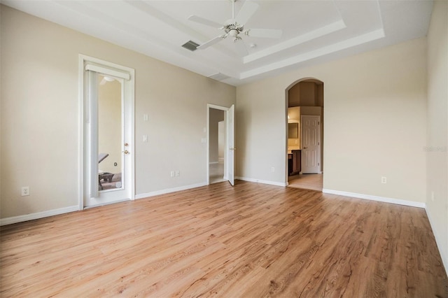 27427 Mistflower Dr, Wesley Chapel, FL 33544 - unfurnished room featuring arched walkways, light wood-style flooring, a ceiling fan, a tray ceiling, and baseboards