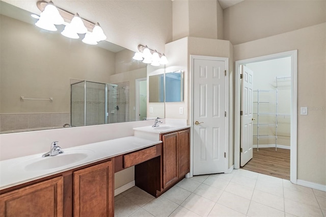 27427 Mistflower Dr, Wesley Chapel, FL 33544 - bathroom with tile patterned floors, a shower stall, double vanity, a spacious closet, and baseboards