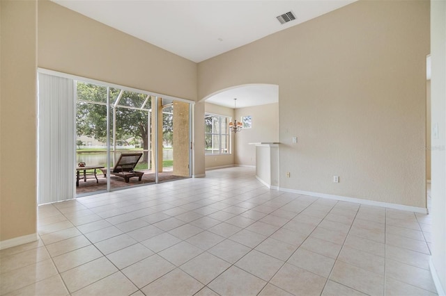 27427 Mistflower Dr, Wesley Chapel, FL 33544 - empty room featuring light tile patterned floors, arched walkways, baseboards, and a chandelier