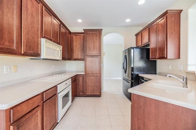 27427 Mistflower Dr, Wesley Chapel, FL 33544 - kitchen featuring white appliances, a sink, arched walkways, light tile patterned flooring, and light countertops