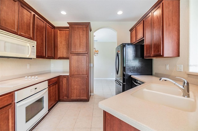 27427 Mistflower Dr, Wesley Chapel, FL 33544 - kitchen featuring white appliances, a sink, light tile patterned floors, arched walkways, and light countertops