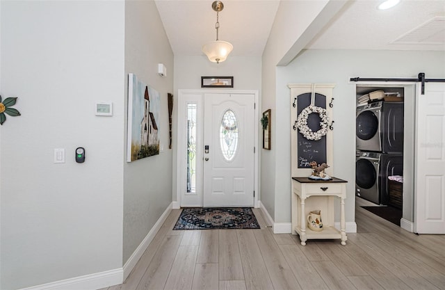 7547 Landmark Dr, Spring Hill, FL 34606 - entryway featuring stacked washing machine and dryer, a barn door, and light wood-style floors