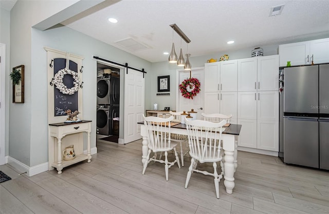 7547 Landmark Dr, Spring Hill, FL 34606 - dining space with stacked washer and clothes dryer, a barn door, light wood-style floors, recessed lighting, and a textured ceiling