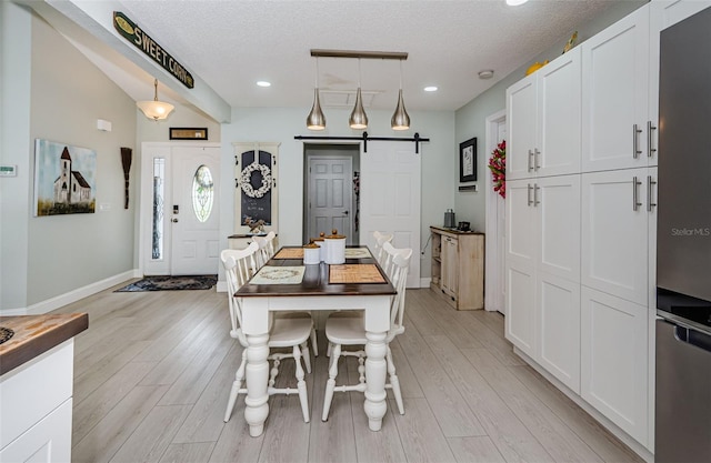 7547 Landmark Dr, Spring Hill, FL 34606 - dining room featuring a barn door, light wood-type flooring, a textured ceiling, and recessed lighting