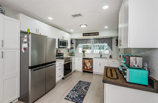 7547 Landmark Dr, Spring Hill, FL 34606 - kitchen with appliances with stainless steel finishes, a textured ceiling, white cabinets, light wood-style flooring, and recessed lighting