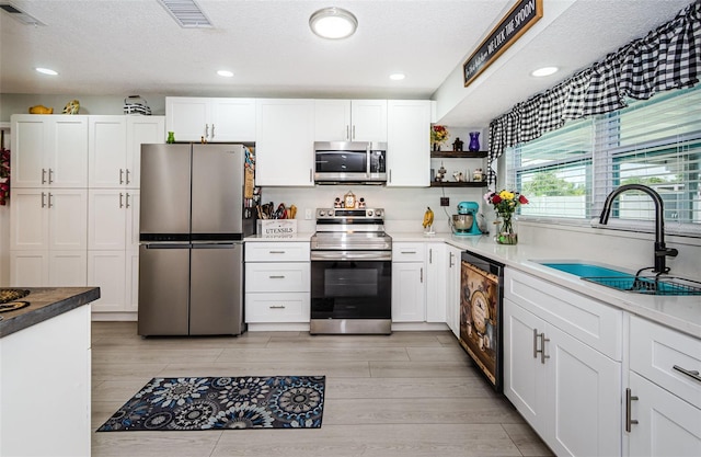 7547 Landmark Dr, Spring Hill, FL 34606 - kitchen featuring appliances with stainless steel finishes, white cabinets, open shelves, light wood-type flooring, and a textured ceiling