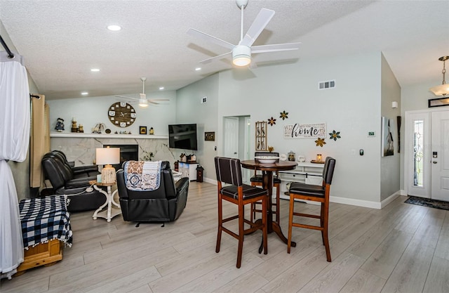 7547 Landmark Dr, Spring Hill, FL 34606 - dining space with vaulted ceiling, a ceiling fan, a textured ceiling, light wood-type flooring, and a premium fireplace
