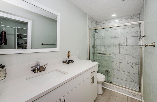 7547 Landmark Dr, Spring Hill, FL 34606 - full bathroom featuring vanity, wood finished floors, a shower stall, a textured ceiling, and a spacious closet