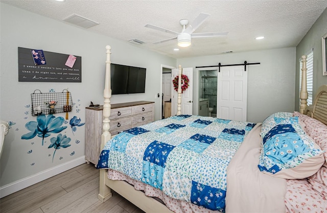 7547 Landmark Dr, Spring Hill, FL 34606 - bedroom featuring wood finished floors, a barn door, a textured ceiling, a ceiling fan, and ensuite bathroom