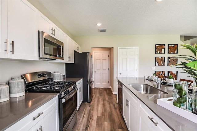 1217 Tidal St, Haines City, FL 33844 - kitchen featuring appliances with stainless steel finishes, a sink, dark countertops, white cabinetry, and dark wood-style floors